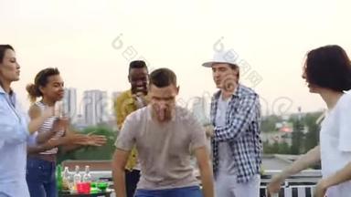 英俊的年轻人在<strong>朋友圈</strong>跳舞，在露天聚会的屋顶上玩得很开心。 庆祝活动